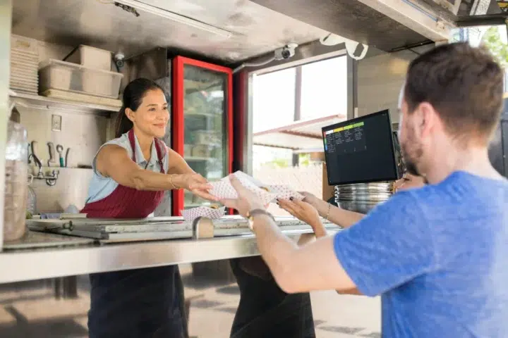 Food truck server handing a meal to a customer.