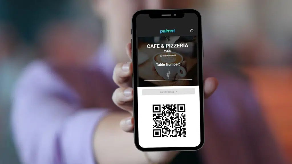 Customer holding phone with Paimnt QR code ordering screen for café and pizzeria.